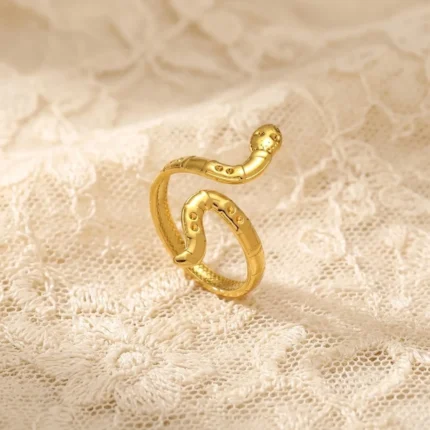 Gold-plated stainless steel adjustable ring shaped like a coiled snake on a lace background
