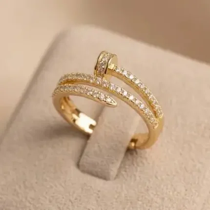 Gold-plated stainless steel adjustable ring with a spiral nail design and embedded clear stones on a satin background.