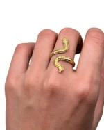 Gold-plated stainless steel adjustable ring shaped like a coiled snake on a lace background