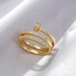 Gold-plated stainless steel adjustable ring with a spiral nail design and embedded clear stones on a satin background.