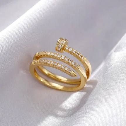 Gold-plated stainless steel adjustable ring with a spiral nail design and embedded clear stones on a satin background.