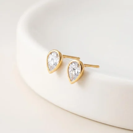 Gold-plated stainless steel teardrop bezel stud earrings with clear stones on a white background