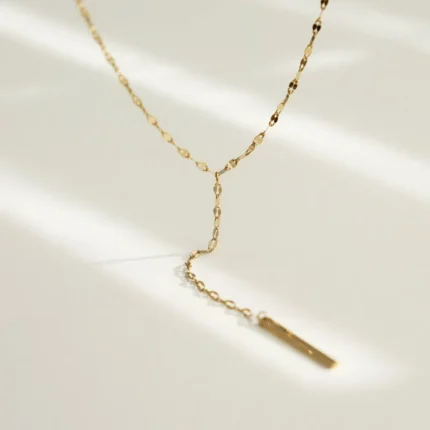 Gold-plated stainless steel lariat necklace with a vertical bar pendant on a white background