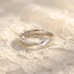 Silver stainless steel twisted mobius adjustable ring on lace background