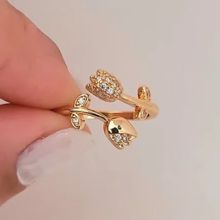 Gold-plated adjustable ring featuring two tulip flowers, one paved with clear stones and one polished, held in hand.