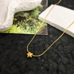 Gold plated stainless steel star pendant necklace on a delicate chain displayed on textured backgrounds
