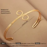 Gold-plated stainless steel spiral loop cuff bracelet on beige fabric background