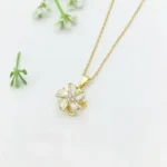 Gold-plated stainless steel necklace featuring a swirling five-petal flower pendant with clear faceted stones on a pink satin background.