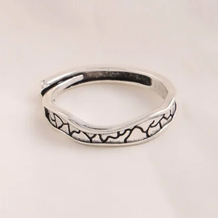 Silver-tone stainless steel ring with black oxidized crackle texture pattern on a cork surface