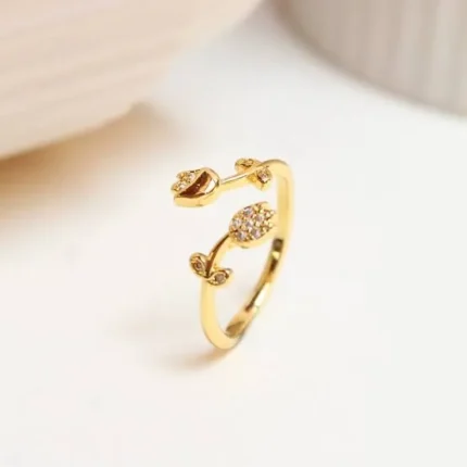 Gold-plated adjustable ring featuring two tulip flowers, one paved with clear stones and one polished, held in hand.