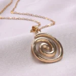 Stainless steel spiral pendant necklace in silver and gold finishes worn by a model