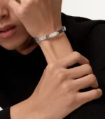 Silver stainless steel bangle bracelet with round clear stone accents on a dark textured background