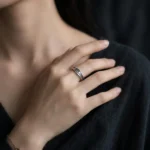 Silver-tone stainless steel ring with black oxidized crackle texture pattern on a cork surface