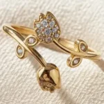 Gold-plated adjustable ring featuring two tulip flowers, one paved with clear stones and one polished, held in hand.