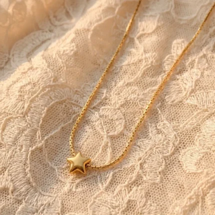 Gold plated stainless steel star pendant necklace on a delicate chain displayed on textured backgrounds