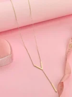 Gold-plated stainless steel Vertex V Lariat Necklace with geometric bar pendant on beige stone background