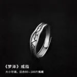 Silver-tone stainless steel ring with black oxidized crackle texture pattern on a cork surface
