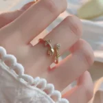 Gold-plated adjustable ring featuring two tulip flowers, one paved with clear stones and one polished, held in hand.