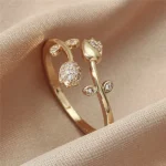 Gold-plated adjustable ring featuring two tulip flowers, one paved with clear stones and one polished, held in hand.