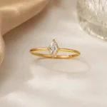 Gold plated stainless steel ring with a small marquise cut clear stone on a thin band