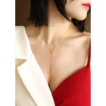 Gold-plated stainless steel Vertex V Lariat Necklace with geometric bar pendant on beige stone background