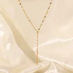 Gold-plated stainless steel lariat necklace with a vertical bar pendant on a white background