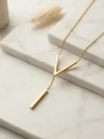 Gold-plated stainless steel Vertex V Lariat Necklace with geometric bar pendant on beige stone background
